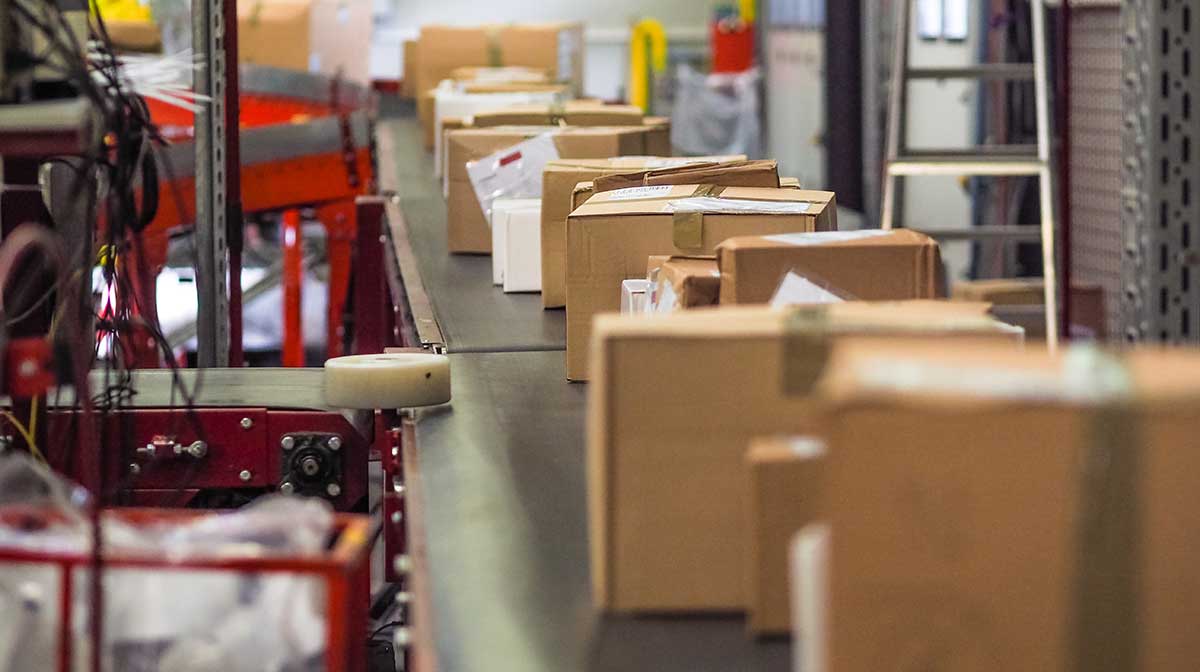 Packages ride along a conveyor belt in a procurement facility